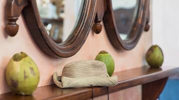 Une étagère en bois sur laquelle sont posés un chapeau tressé et deux fruits verts.