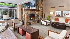 Un salon moderne avec une cheminée en pierre, des sièges confortables et des œuvres d’art accrochées aux murs.