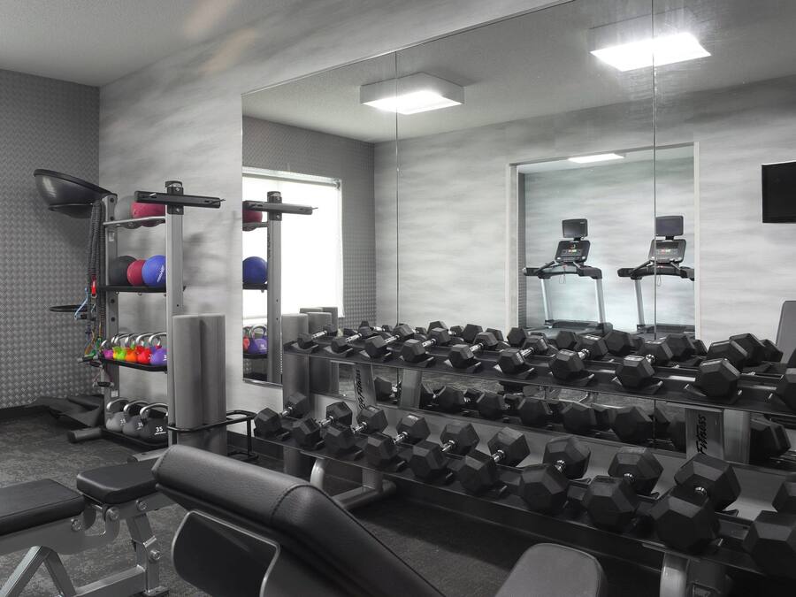 A gym with various exercise equipment, including dumbbells and a treadmill.