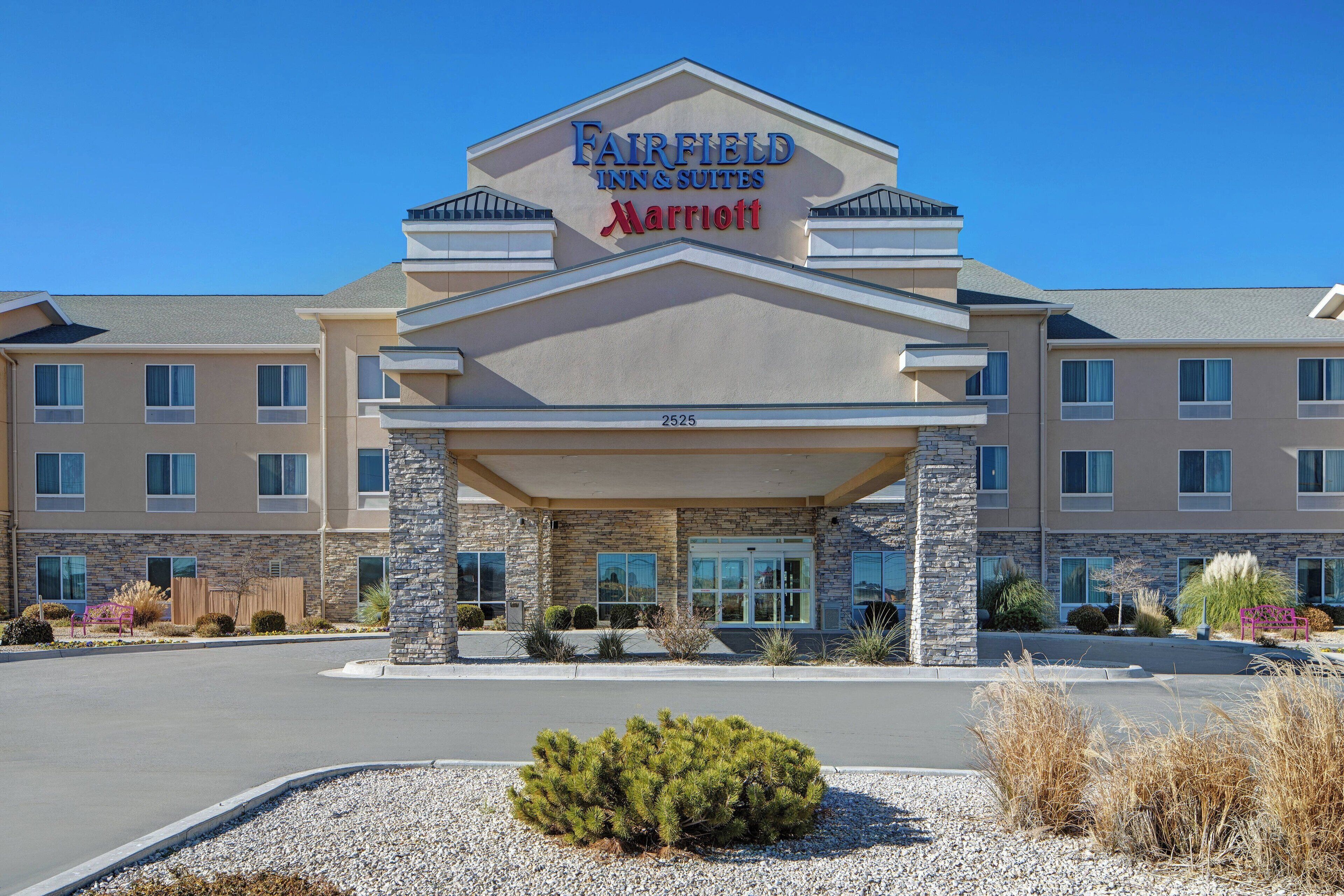 Un hotel Fairfield Inn & Suites Marriott con facciata in pietra, numerose finestre e cielo sereno.
