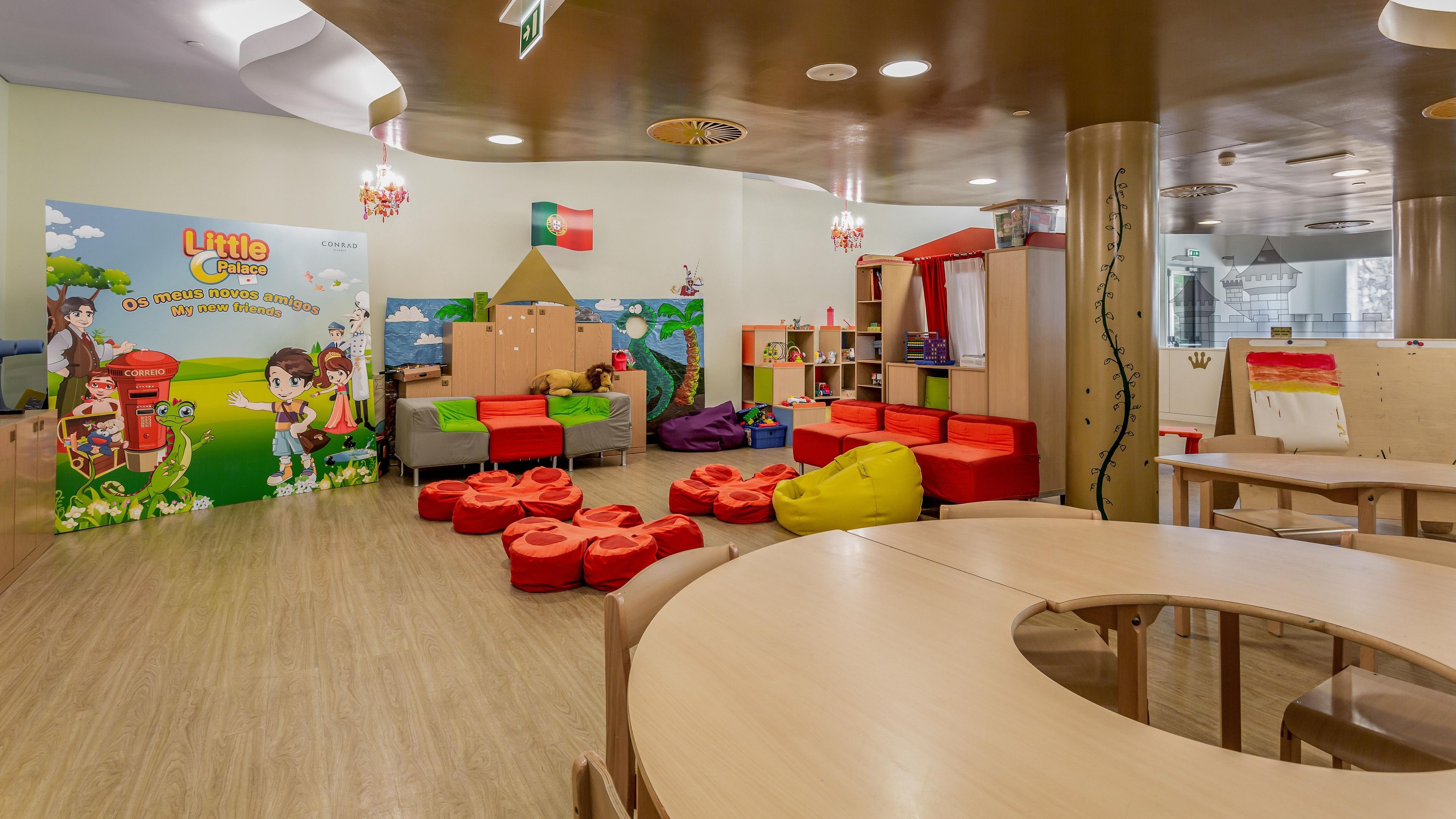 Un cuarto de juegos infantil con mobiliario colorido, un mural y una bandera portuguesa.