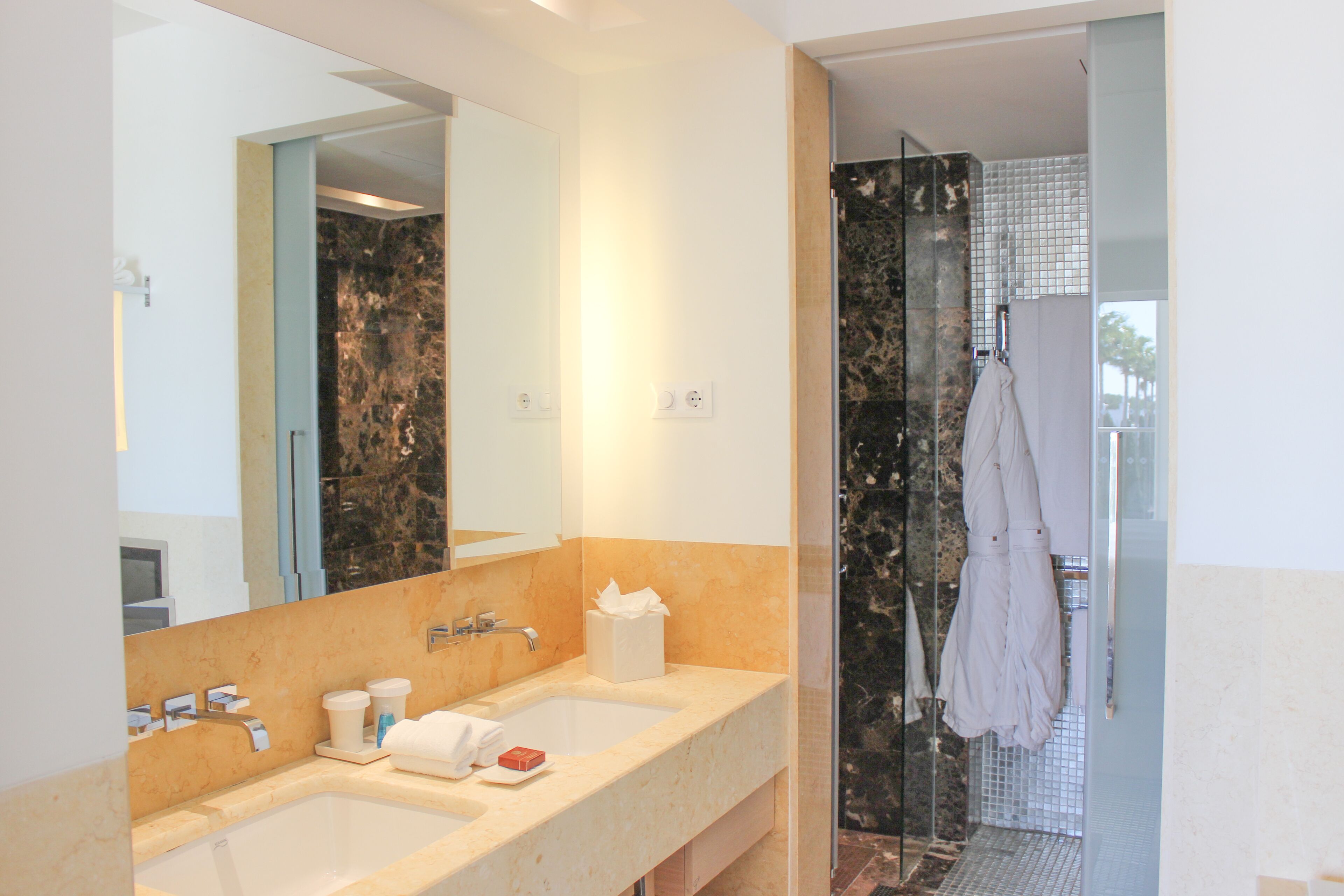 Un baño con lavamanos doble, un espejo grande y cabina de ducha de vidrio.