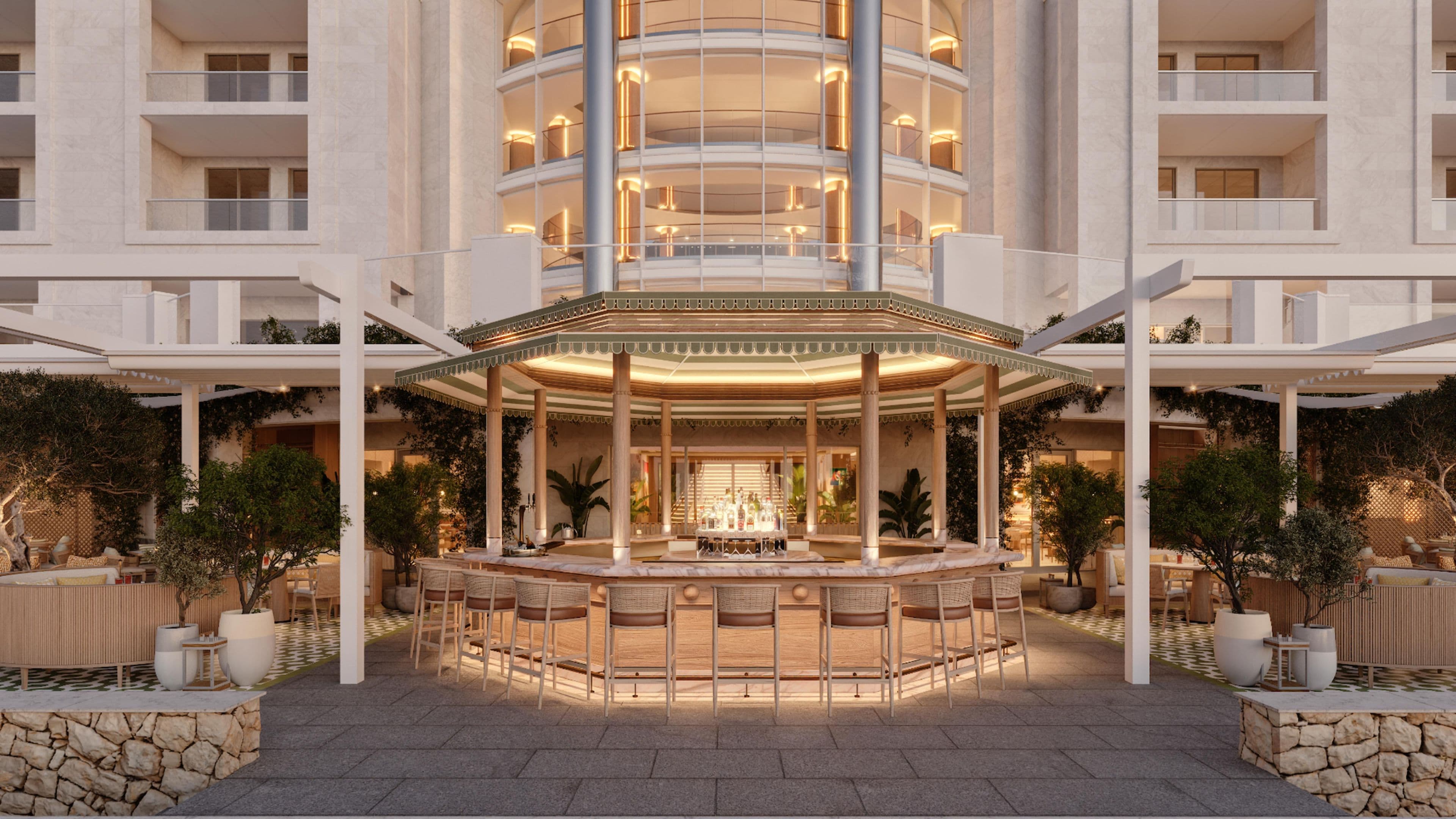 Hotel de varios pisos con un patio central que incluye un bar y una zona de estar, rodeado de balcones y abundante vegetación.
