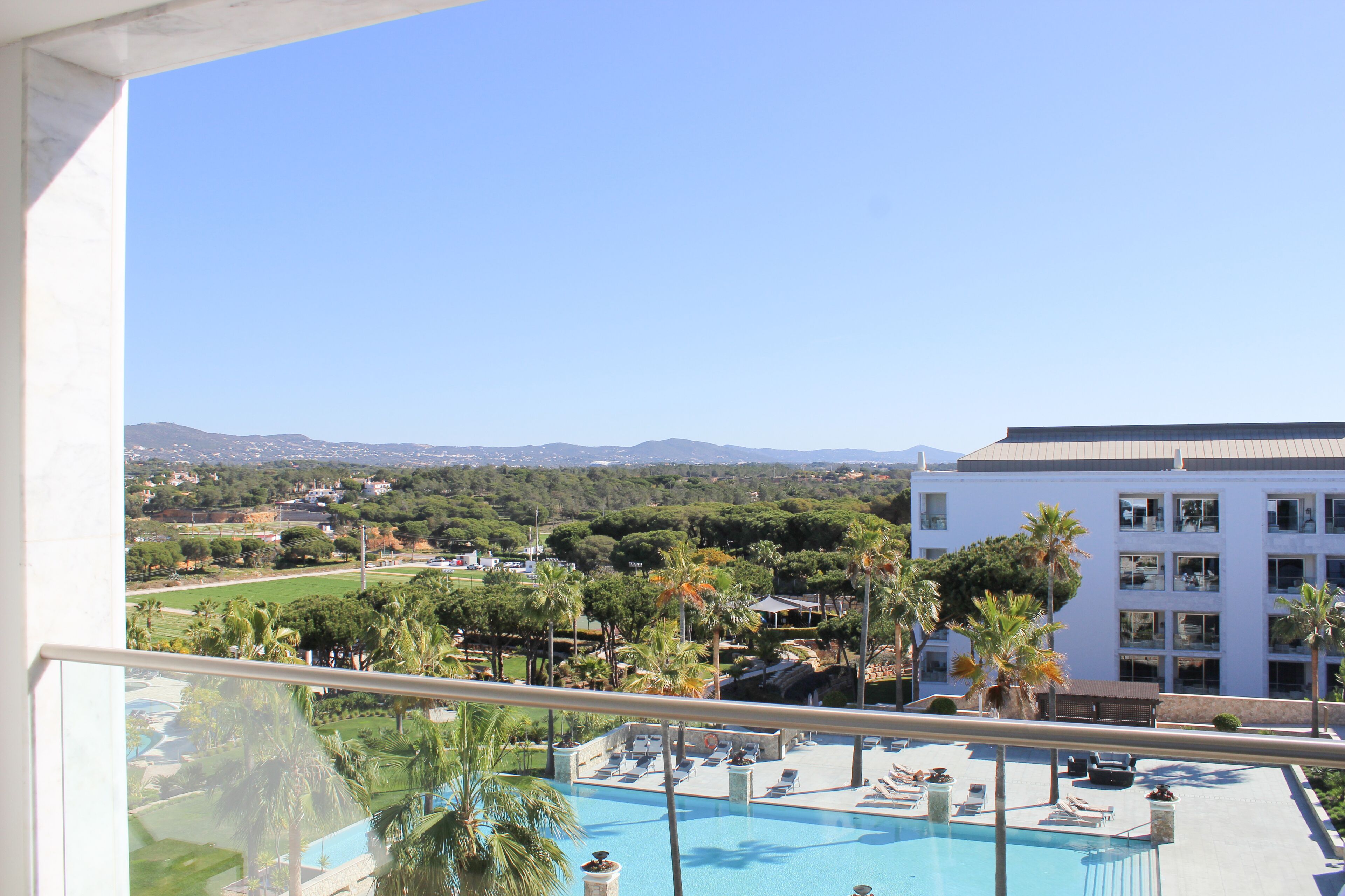 Un espace piscine doté de chaises longues et offrant une vue sur un paysage montagneux.