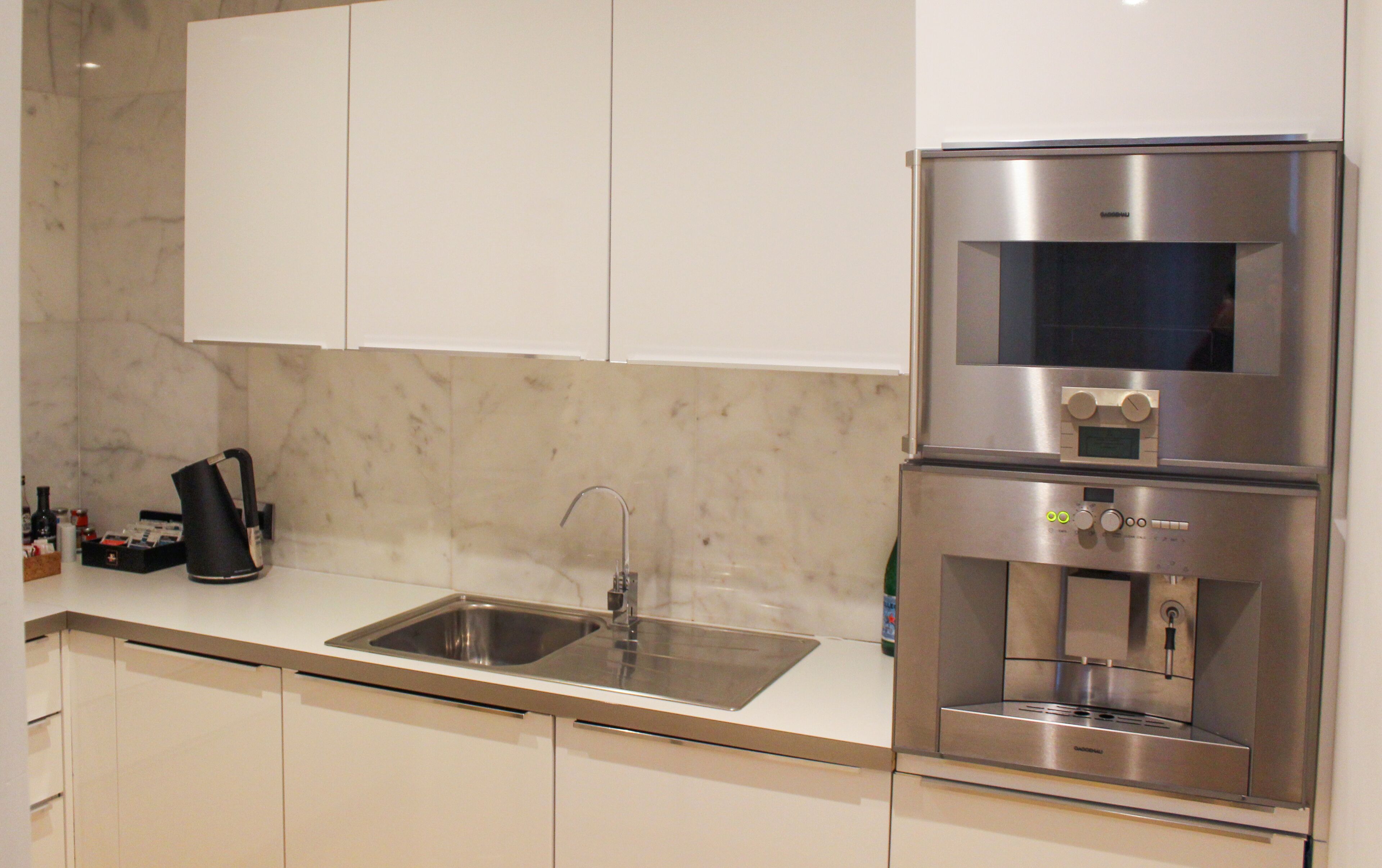 Una cocina moderna con un refrigerador de acero inoxidable, un horno empotrado y un lavamanos.