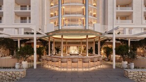 A multi-story hotel with a central courtyard featuring a bar and seating area, surrounded by balconies and lush greenery.