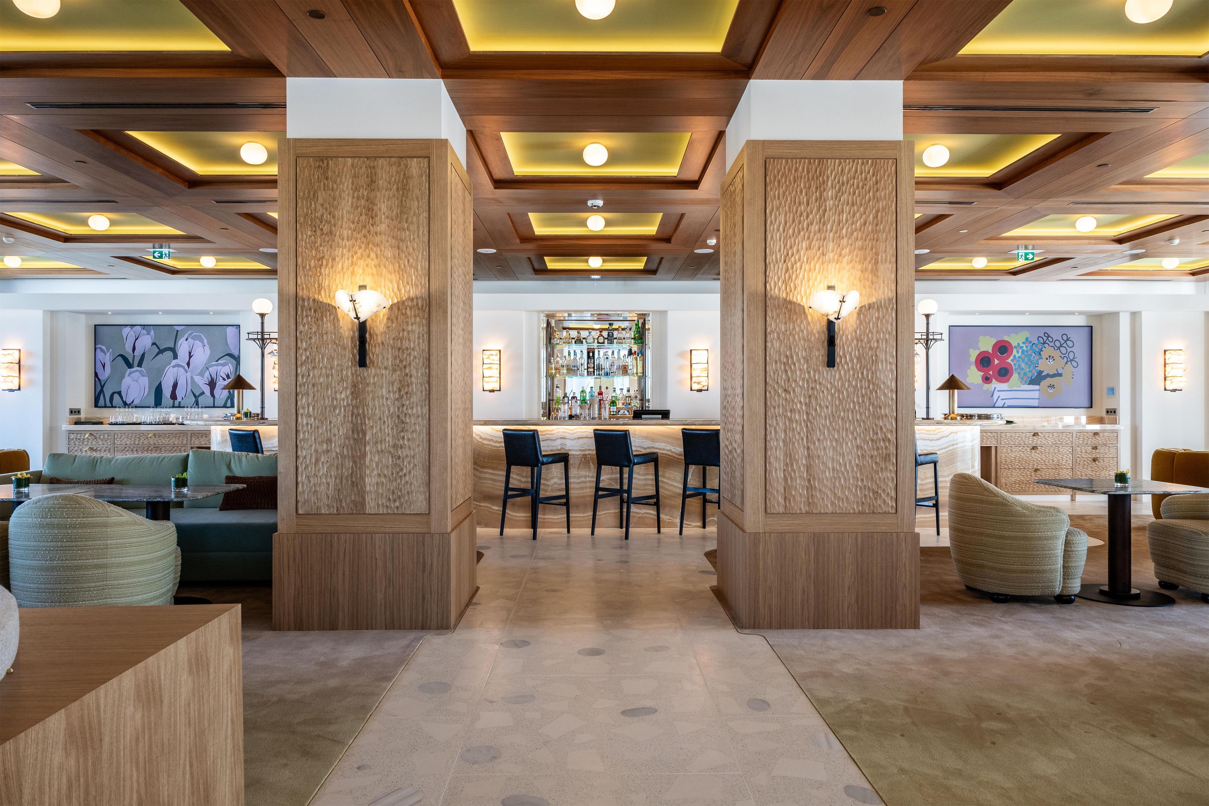A modern bar area with wooden accents, bar stools, and a central bar counter.