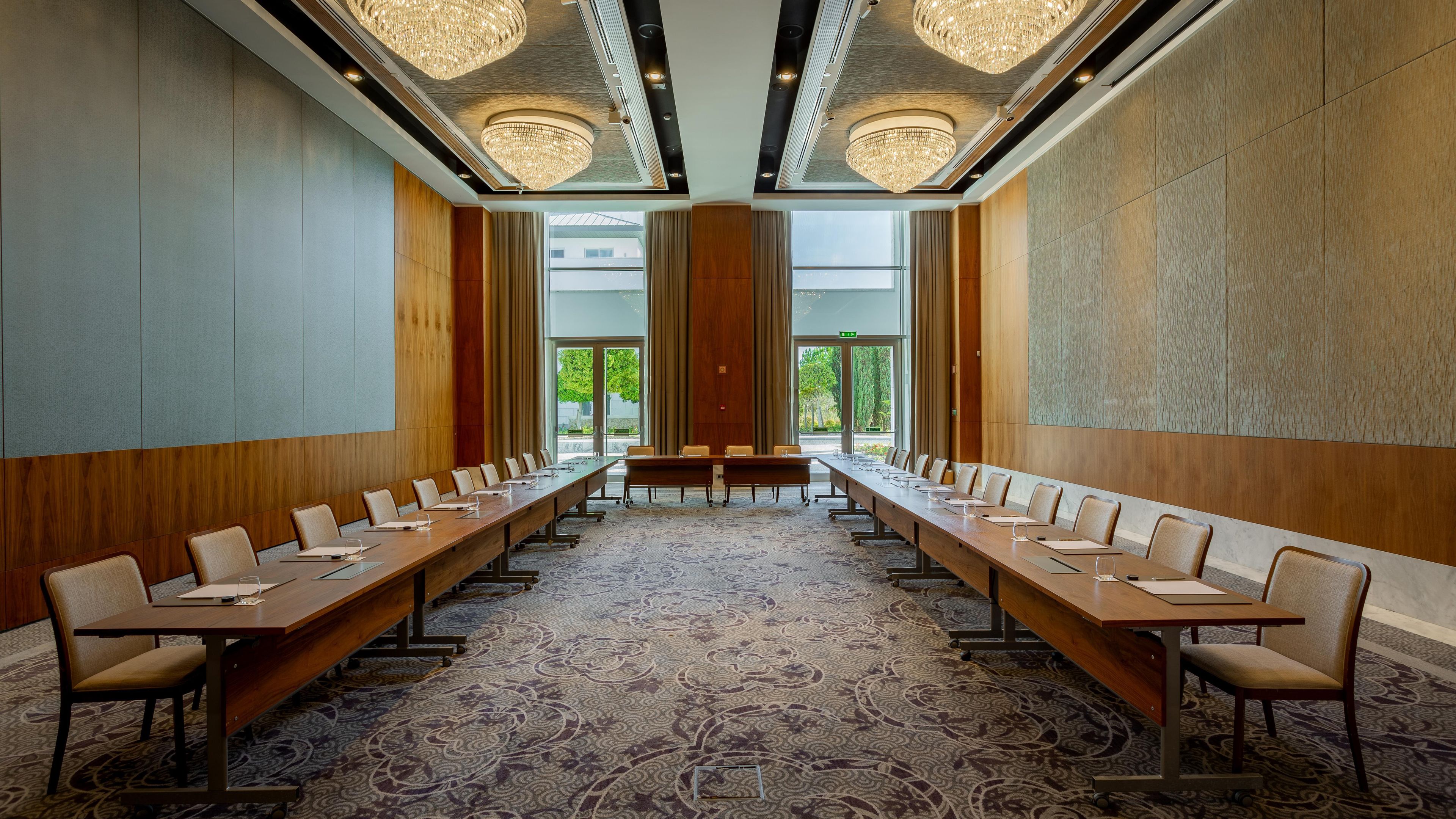 A conference room with a long table, chairs, and a patterned carpet.