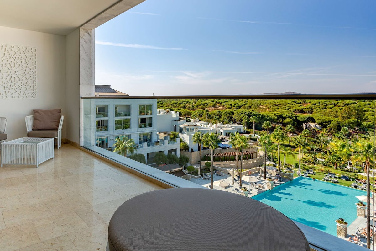 A balcony with a view of a pool and lush greenery.
