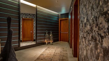 A modern hallway with wooden doors, a woven chair, and a patterned rug.