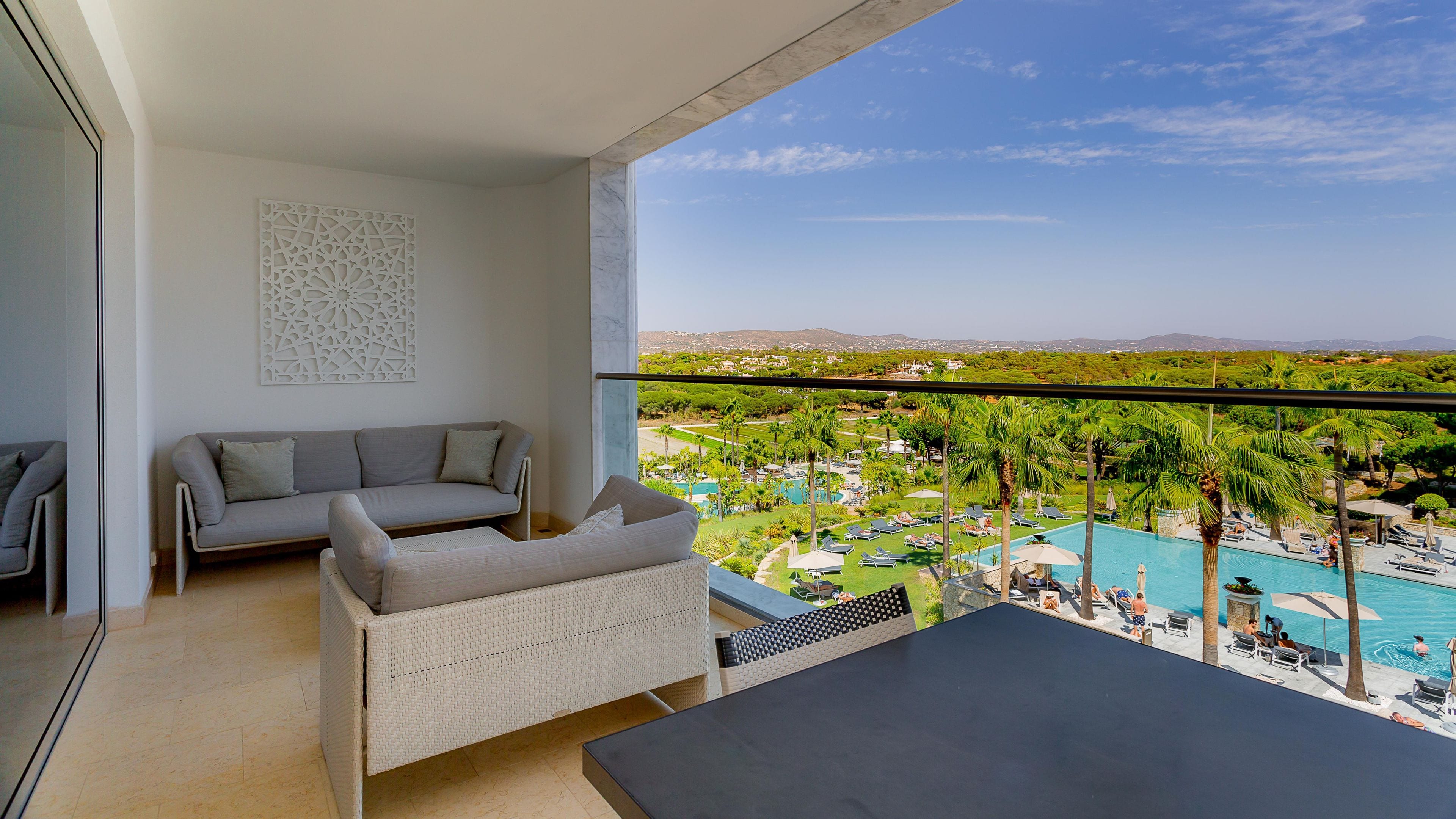 Un balcón con vistas a una piscina y al área del resort, un sofá y una mesa de comedor.