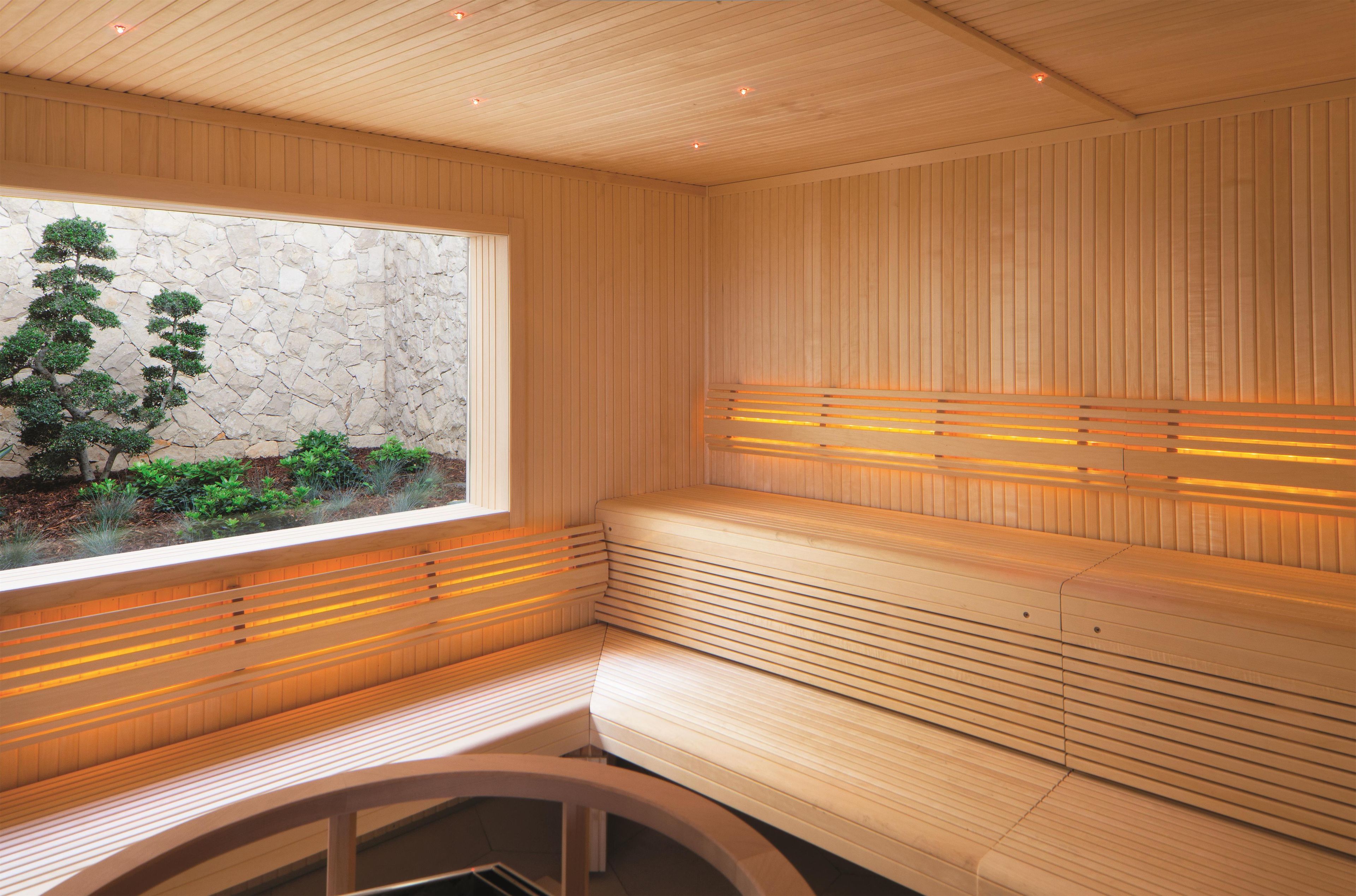 A sauna with wooden benches and a stone wall.