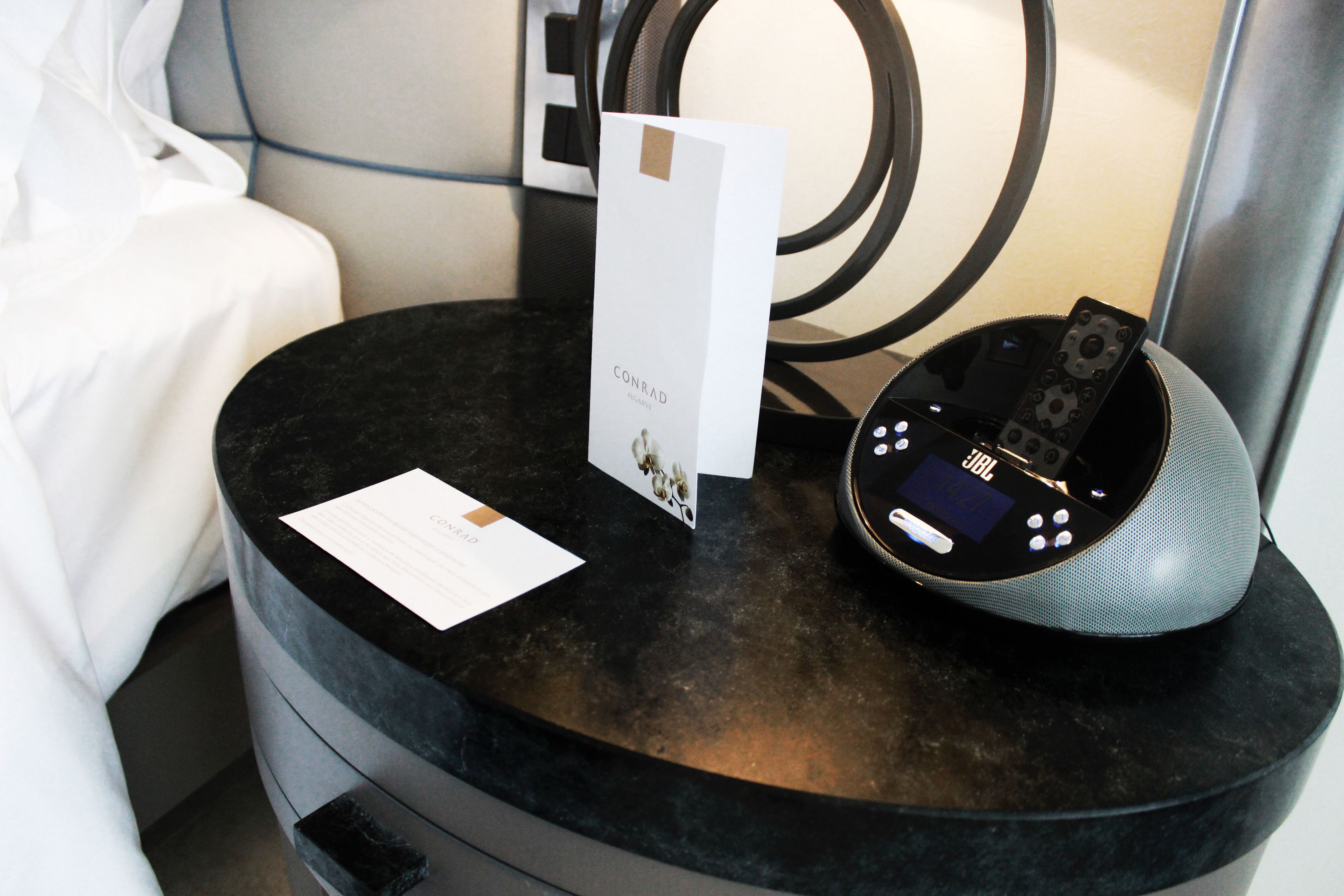 A black round table with a JBL speaker, a card, and a small booklet.