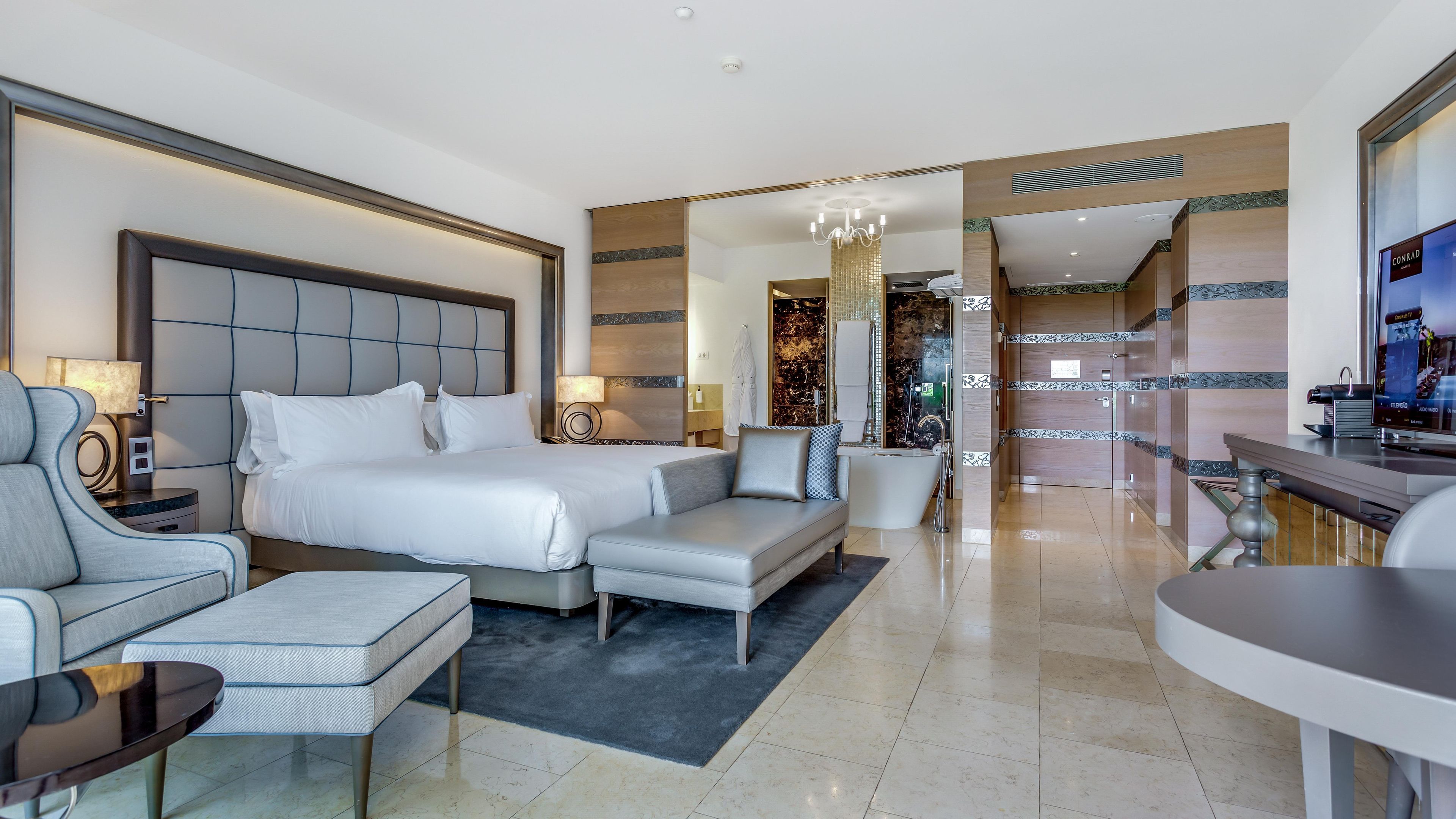 Una habitación de hotel con una cama grande, un sofá, un escritorio y un televisor.