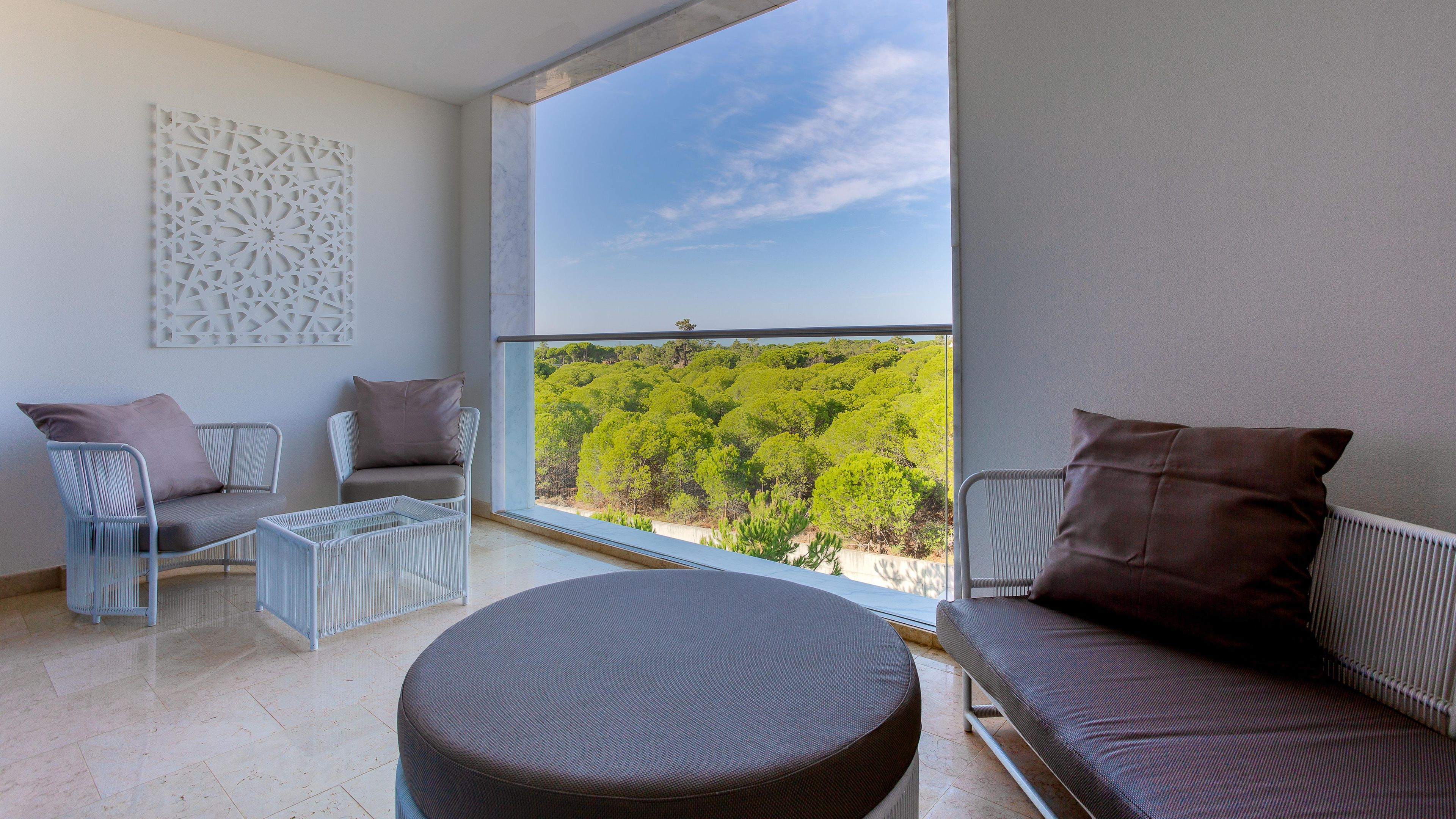 Un balcón con vistas a un paisaje verde, amueblado con un sofá, sillas y una mesita.