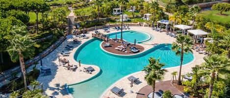 Ein Resort mit einem großen Pool, Liegestühlen und Palmen.