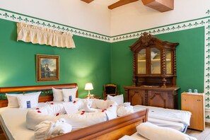 A hotel room with a large bed, a wooden dresser, a mirror, and a green wall with a decorative border. - Hotel Burg Trendelburg (Trendelburg)