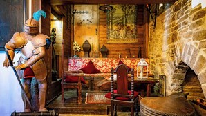 A medieval-themed room with a knight statue, wooden furniture, a stone wall, and a tapestry. - Hotel Burg Trendelburg (Trendelburg)