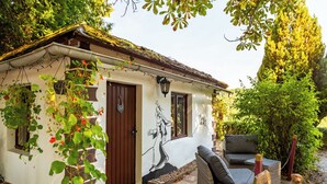A small house with a white exterior, a brown door, and a mural of a woman. There is a wicker sofa and a small dog outside. - Hotel Burg Trendelburg (Trendelburg)