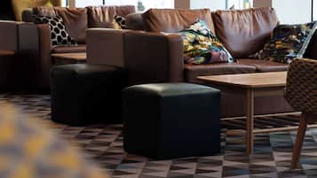 A modern lounge area with leather sofas, patterned cushions, and a geometric patterned floor.