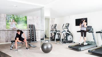 A gym with exercise equipment, a bench, and a large exercise ball.