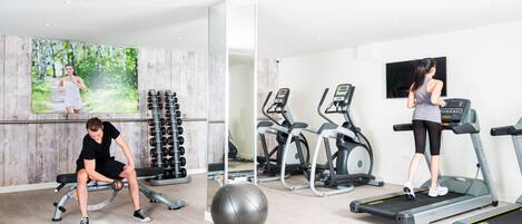 A gym with exercise equipment, a bench, and a large exercise ball.