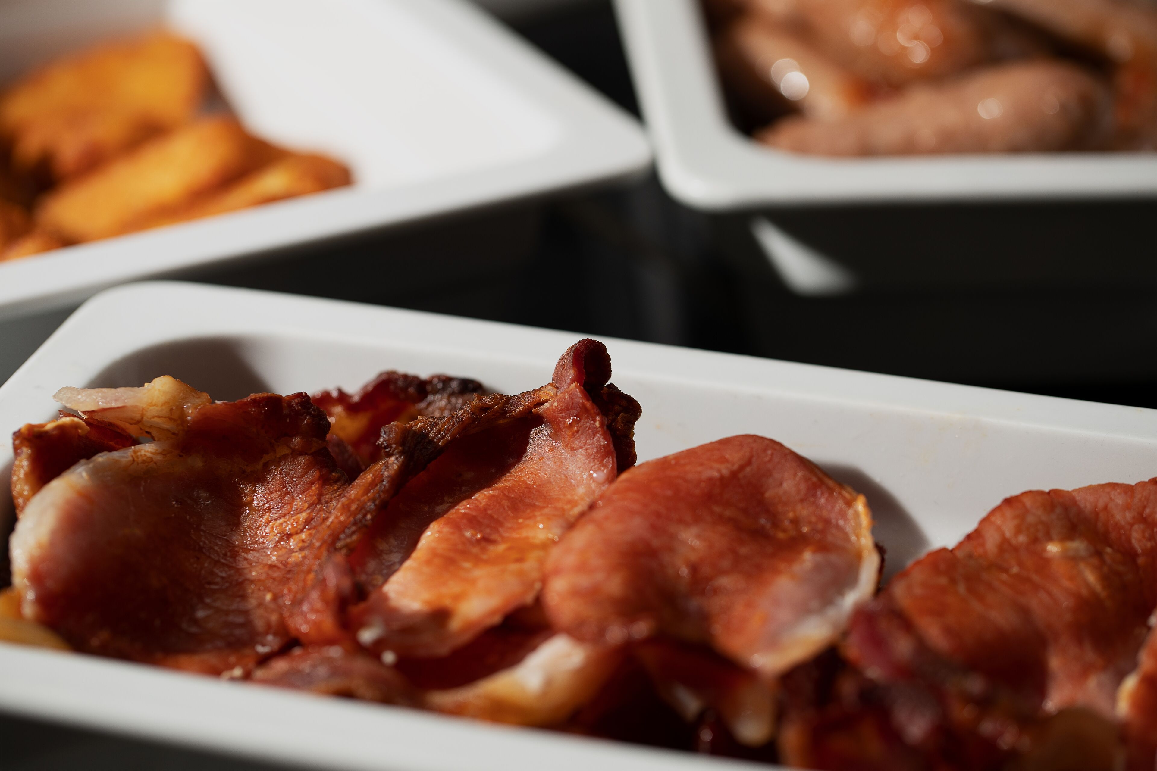 En vit, rektangulär tallrik med krispiga baconskivor.