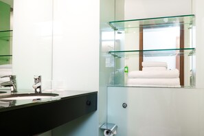 A modern bathroom with a glass shower enclosure, a black sink, and a white towel.