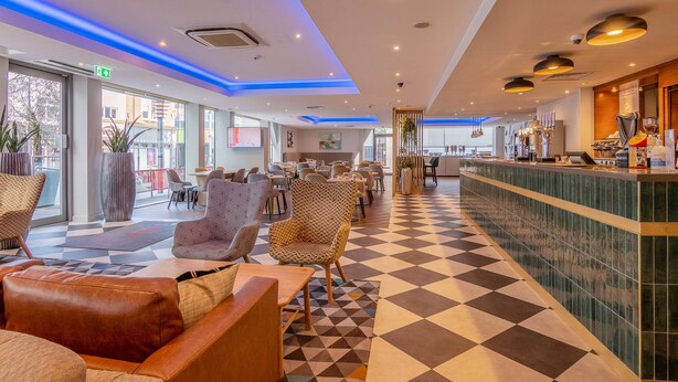 Un hall de hotel con piso a cuadros, zona de estar y un bar.
