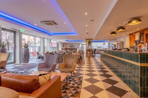 A hotel lobby with a checkered floor, seating area, and a bar. - Ramada Encore by Wyndham Leicester City Centre (Leicester)