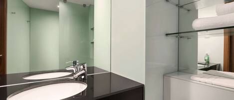 A modern bathroom with two sinks, a mirror, and a glass shower enclosure.