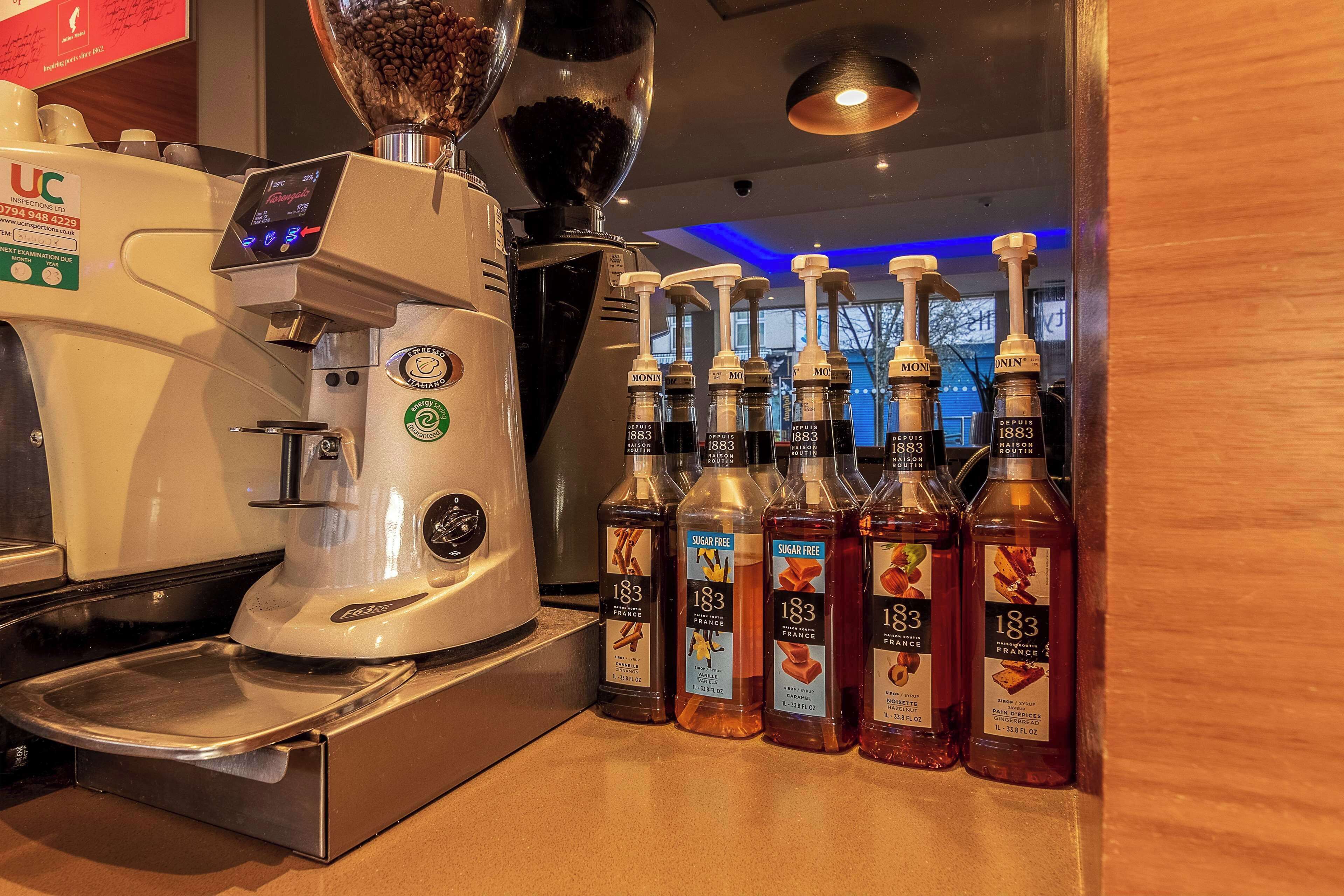 Une machine à café et des bouteilles de sirop de la marque 183 sont posées sur un comptoir.
