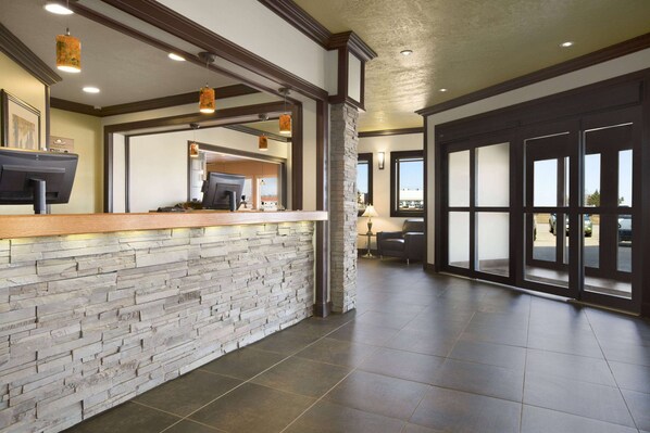 A reception area with a stone wall, wooden counter, and a view of the outside through large glass doors.