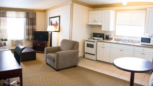 A compact hotel room with a living area, kitchenette, and a small dining table. - Days Inn by Wyndham High Level (High Level)