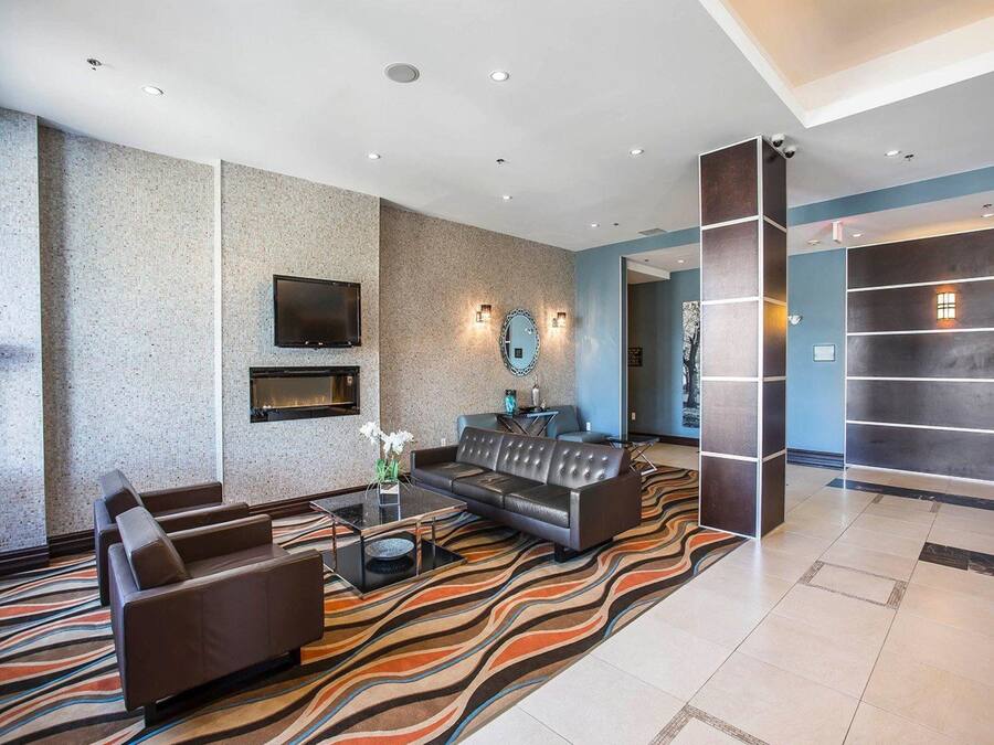A modern lobby with a seating area, a fireplace, and a large mirror.