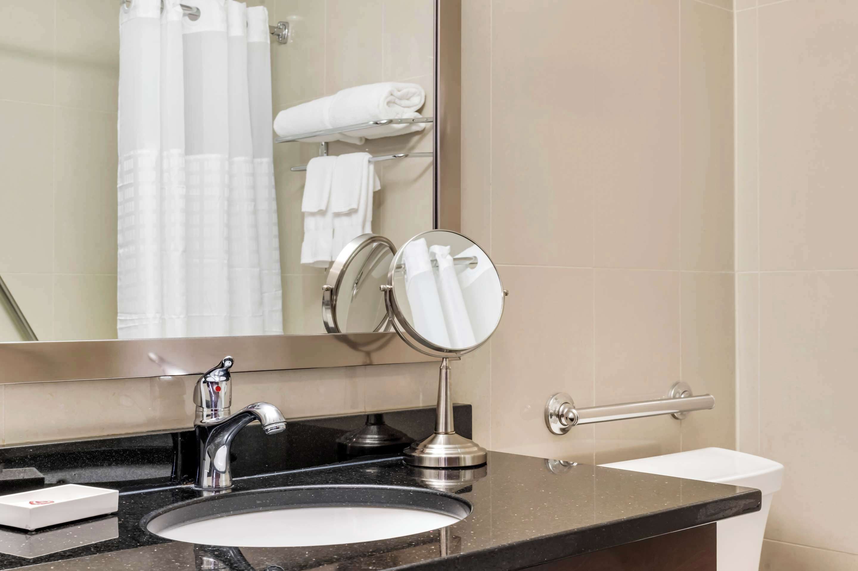 Een badkamer met een wastafel, spiegel, handdoekrek en toilet.