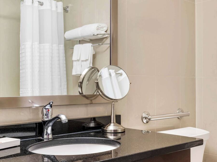 A bathroom with a sink, mirror, towel rack, and toilet.