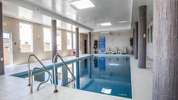 Una piscina interior con normas claras, una silla de socorrista y suelo de baldosas.