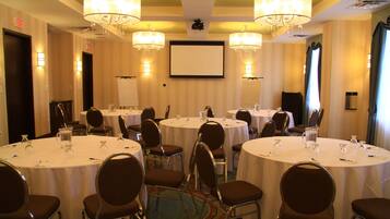 A conference room with multiple round tables, chairs, and chandeliers.