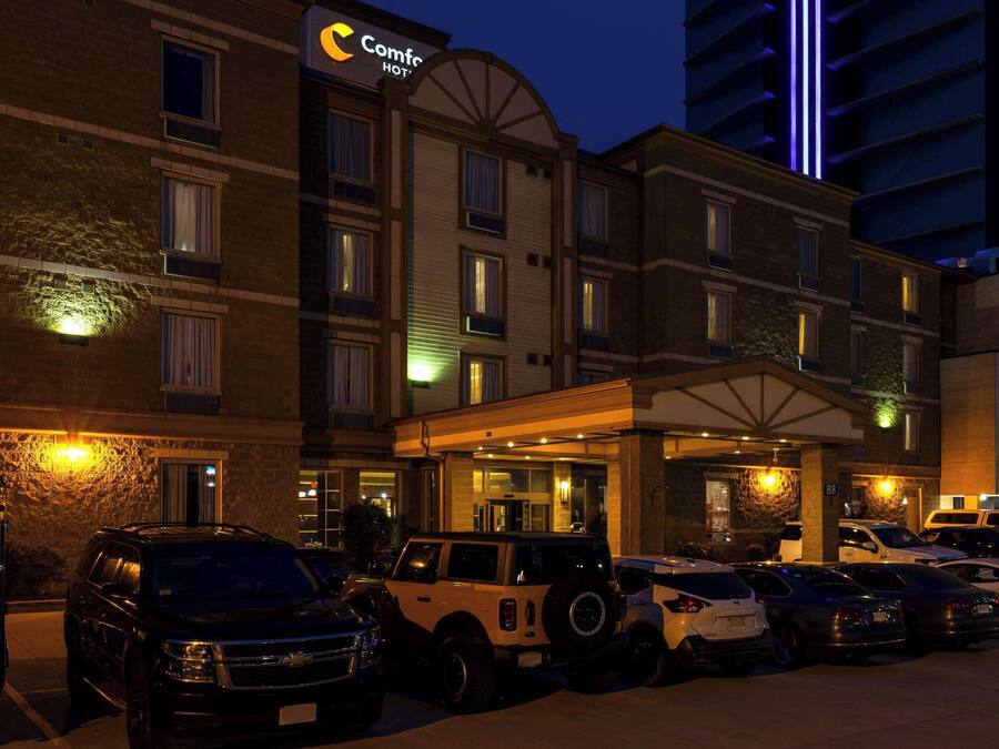 Een hotel met een parkeerplaats vol met verschillende voertuigen, waaronder SUV's en auto's.