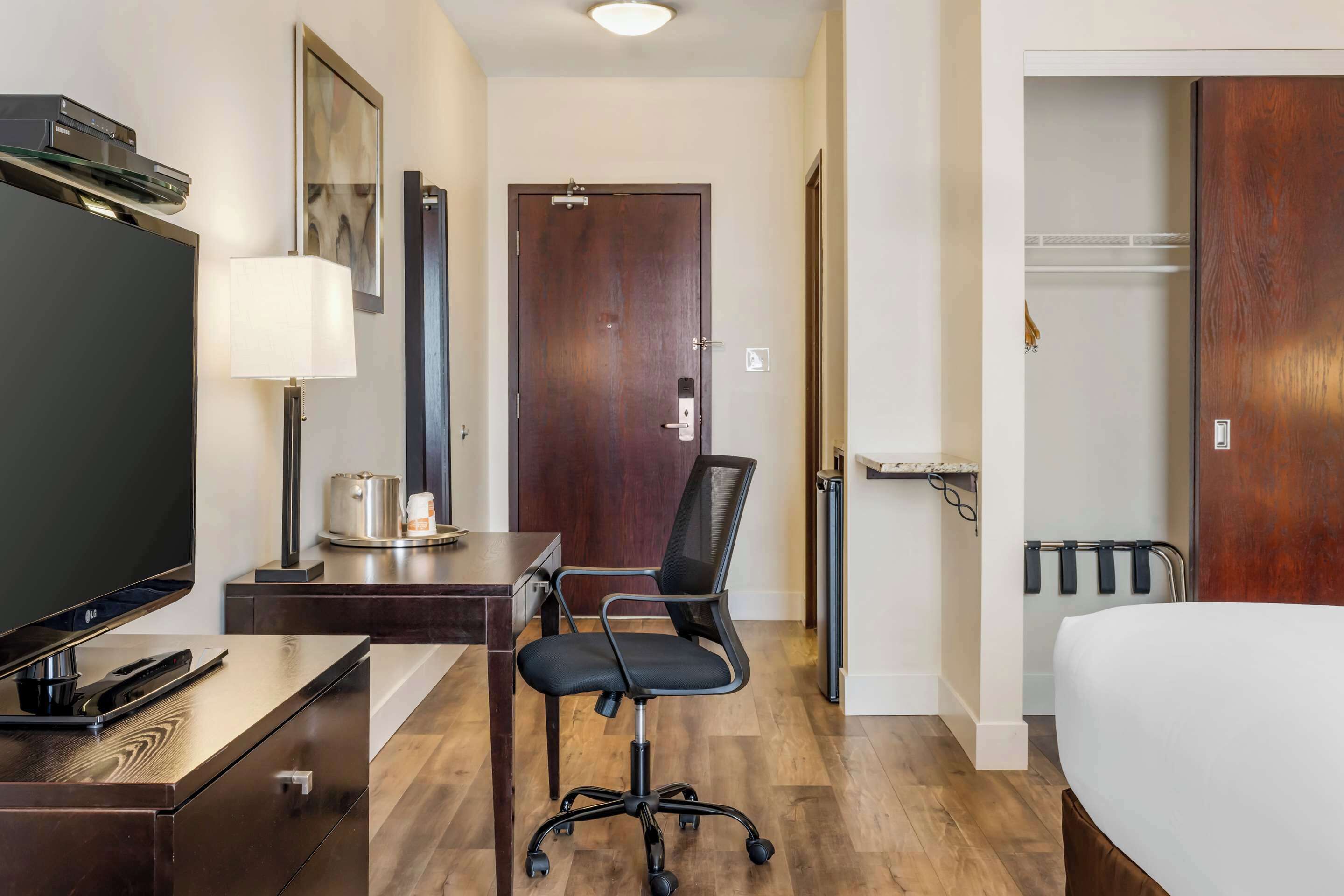 Hotelkamer met een bed, bureau met een flatscreen televisie, stoel, lamp en kapstok.