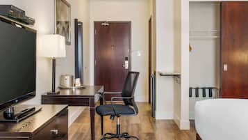 Hotelkamer met een bed, bureau met een flatscreen televisie, stoel, lamp en kapstok.