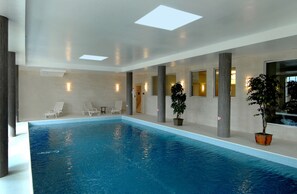 Una piscina techada, sillones reclinables de piscina