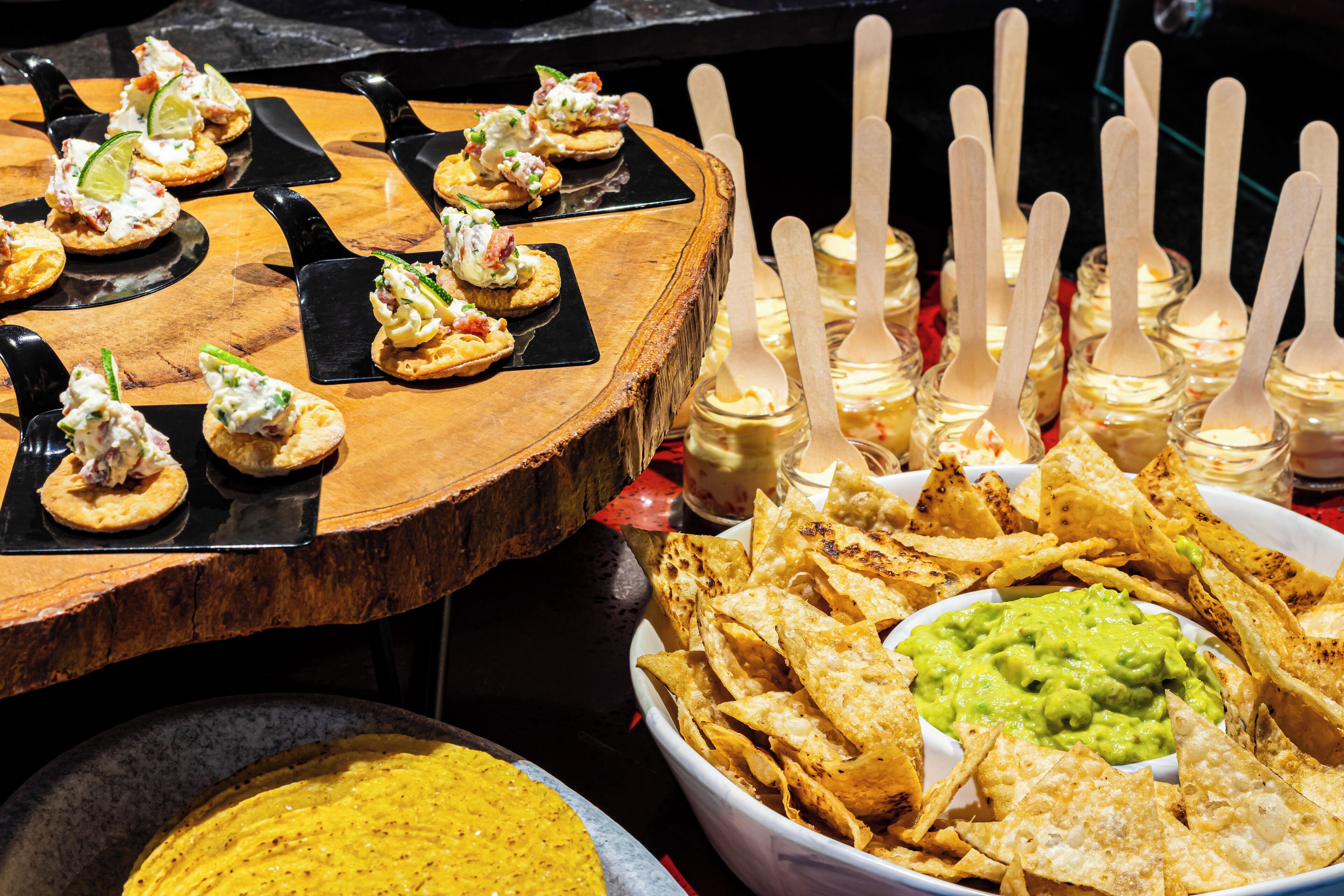A buffet with nachos, guacamole, and various dips.