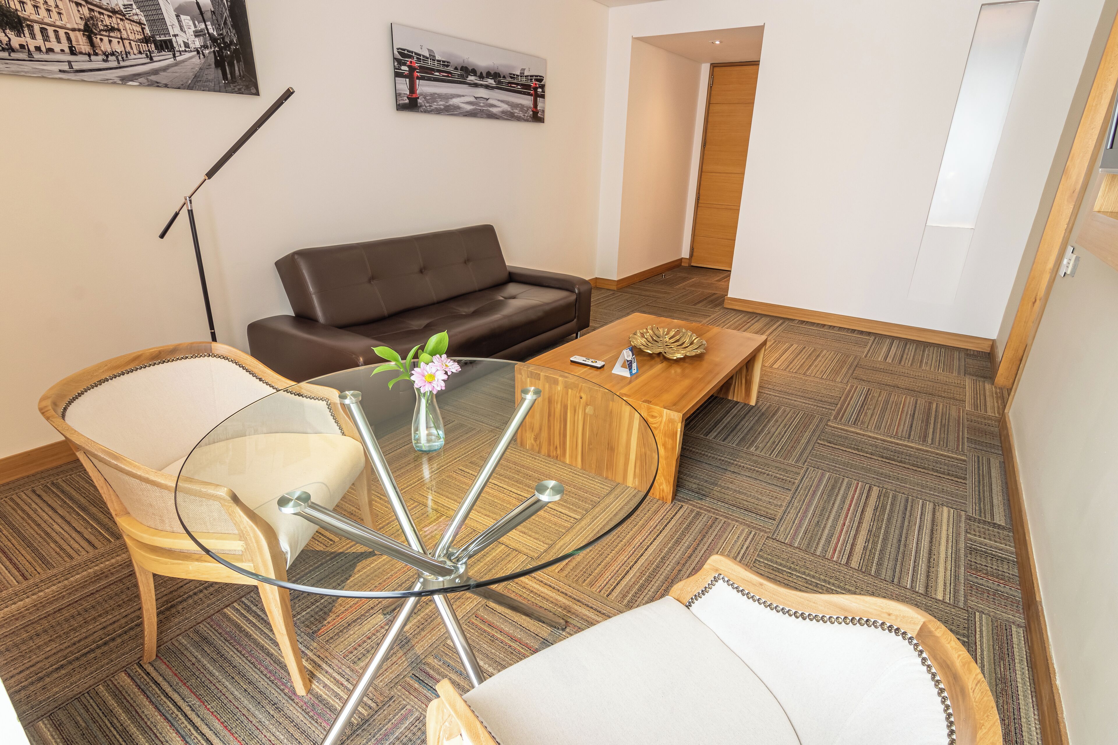 A modern living room with a glass coffee table, a brown leather sofa, and a wooden coffee table.