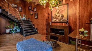 A wooden-floored living room with a fireplace, a staircase, and a blue cushioned bench. - Sonesta Hotel Bogota (Bogotá)