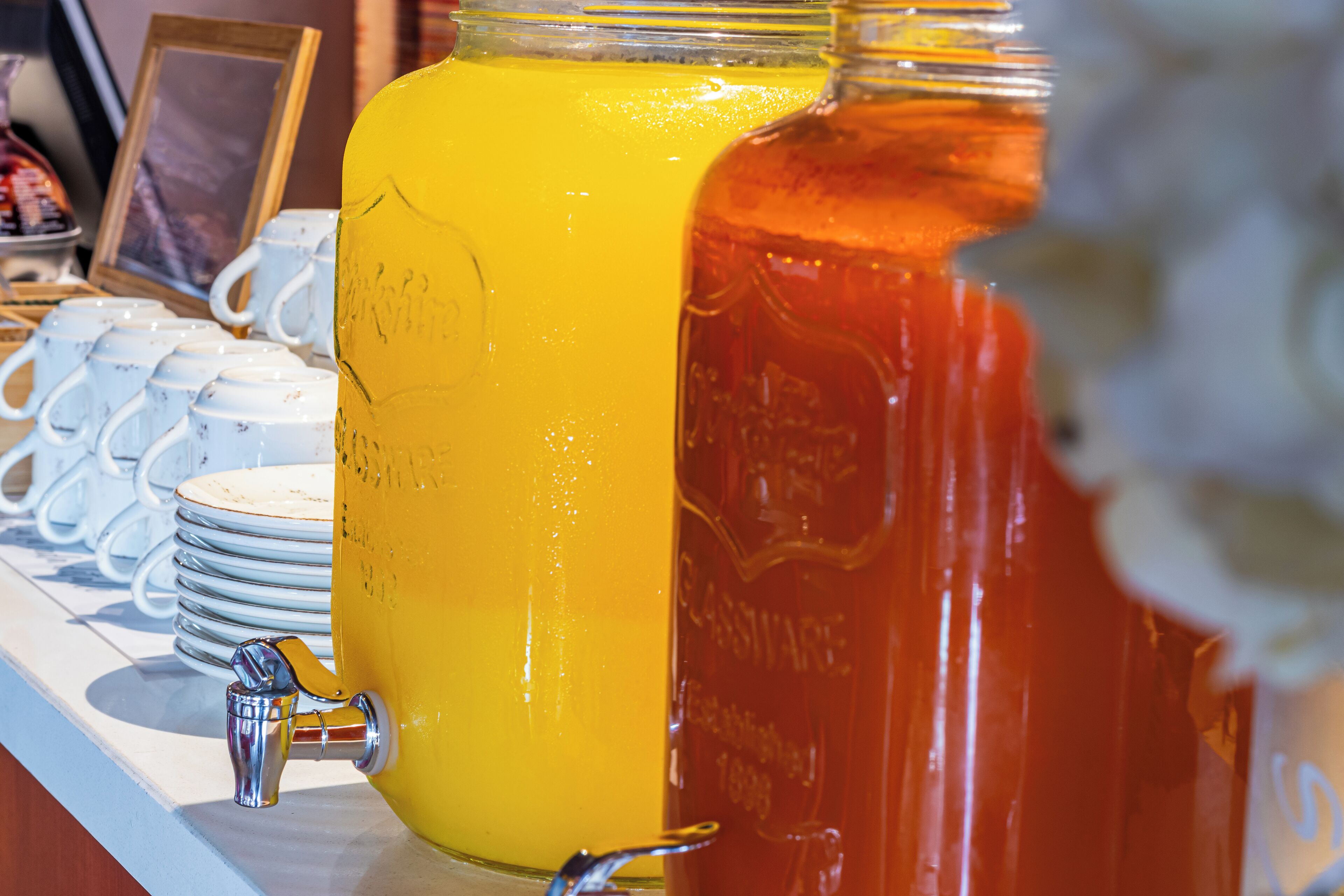 A beverage station with two large jugs, one yellow and one red, and a water fountain.