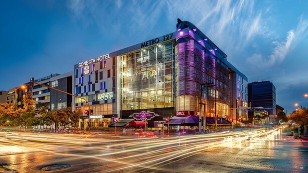 A modern hotel with a glass facade, located at an urban intersection with visible traffic. - Sonesta Hotel Bogota (Bogotá)