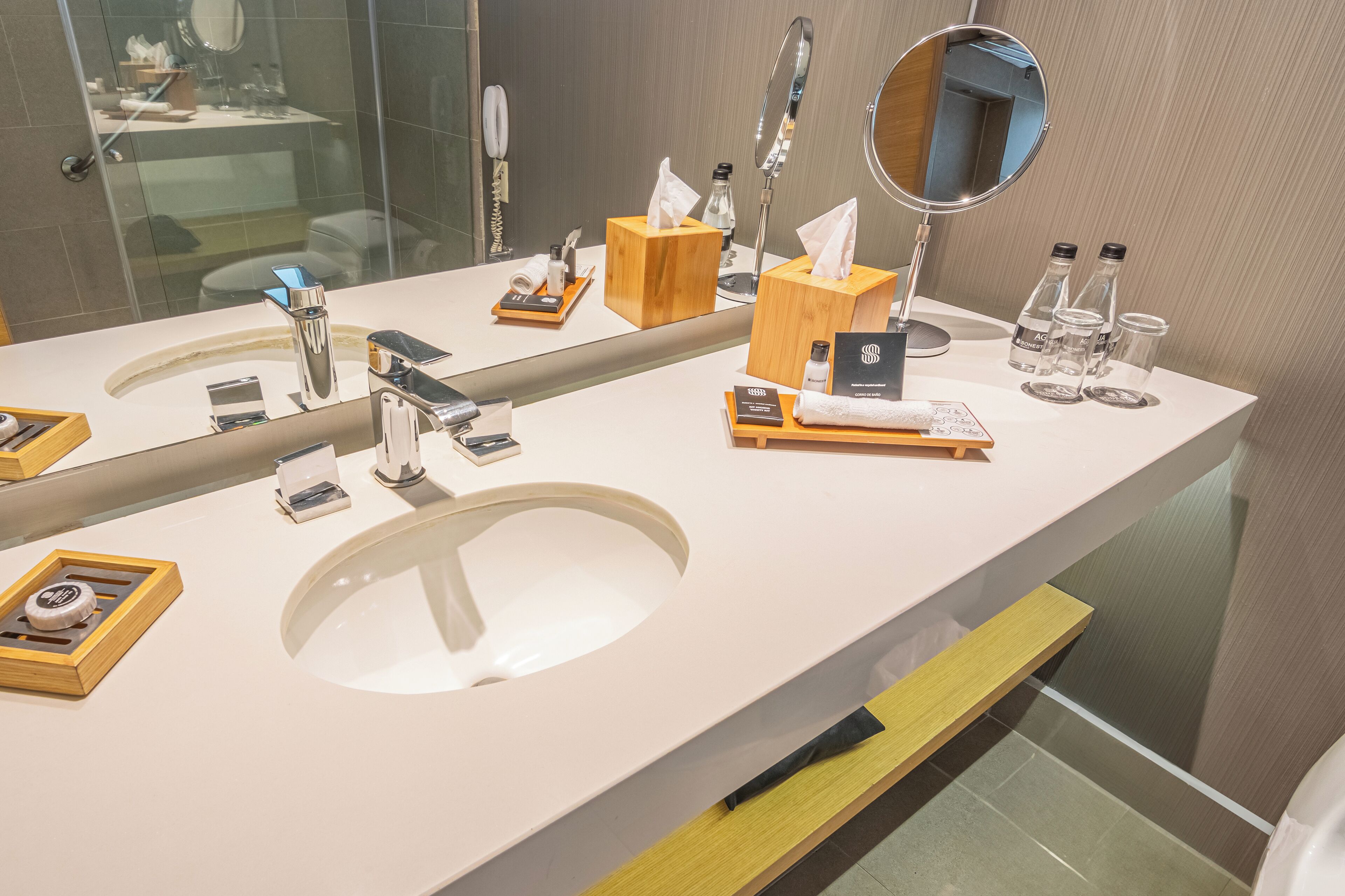 A modern bathroom with a large mirror, two sinks, and various toiletries.