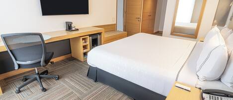 A hotel room with a bed, desk, chair, and a television.